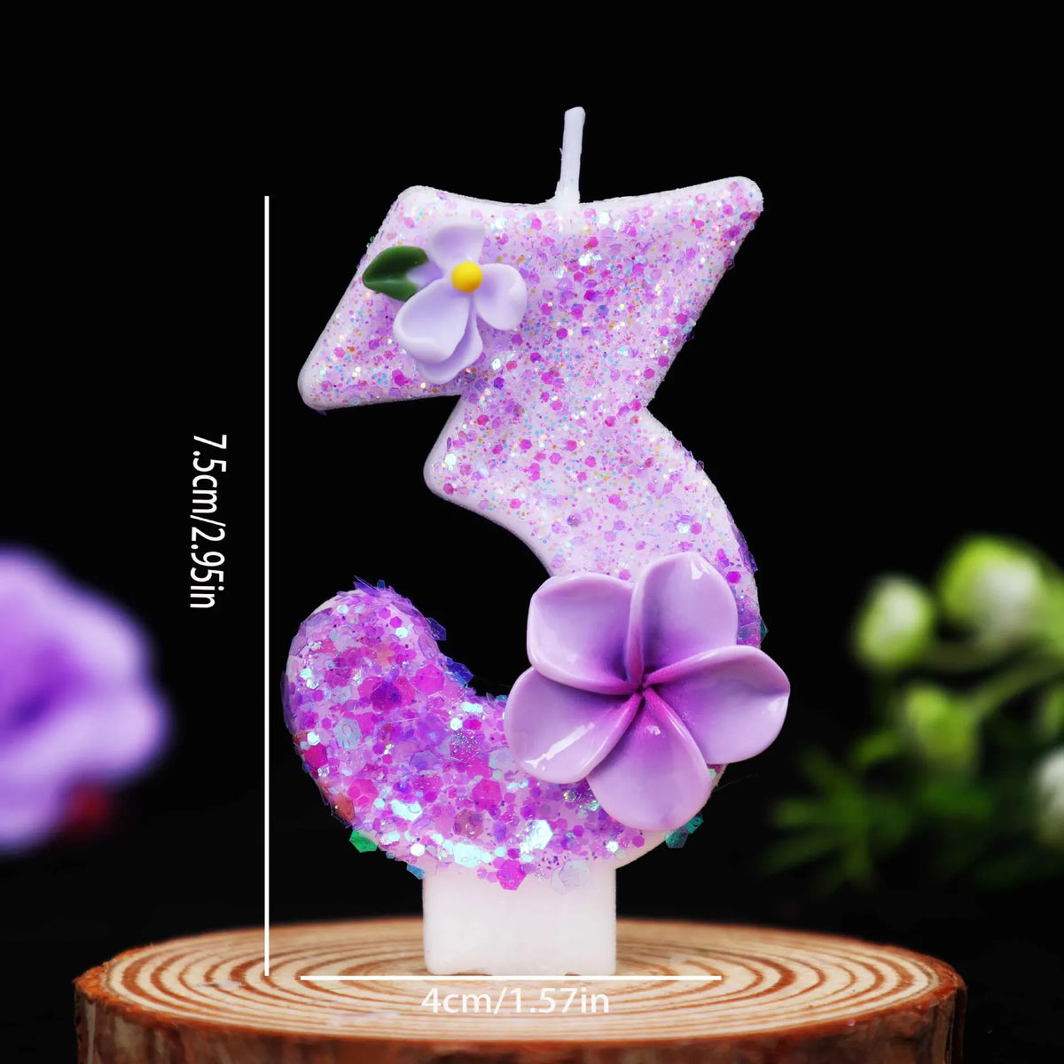 A purple glitter flower number candle shaped like the number three on a wooden surface.