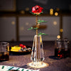 A handcrafted crystal glass rose vase with golden leaves stands on a dark surface.
