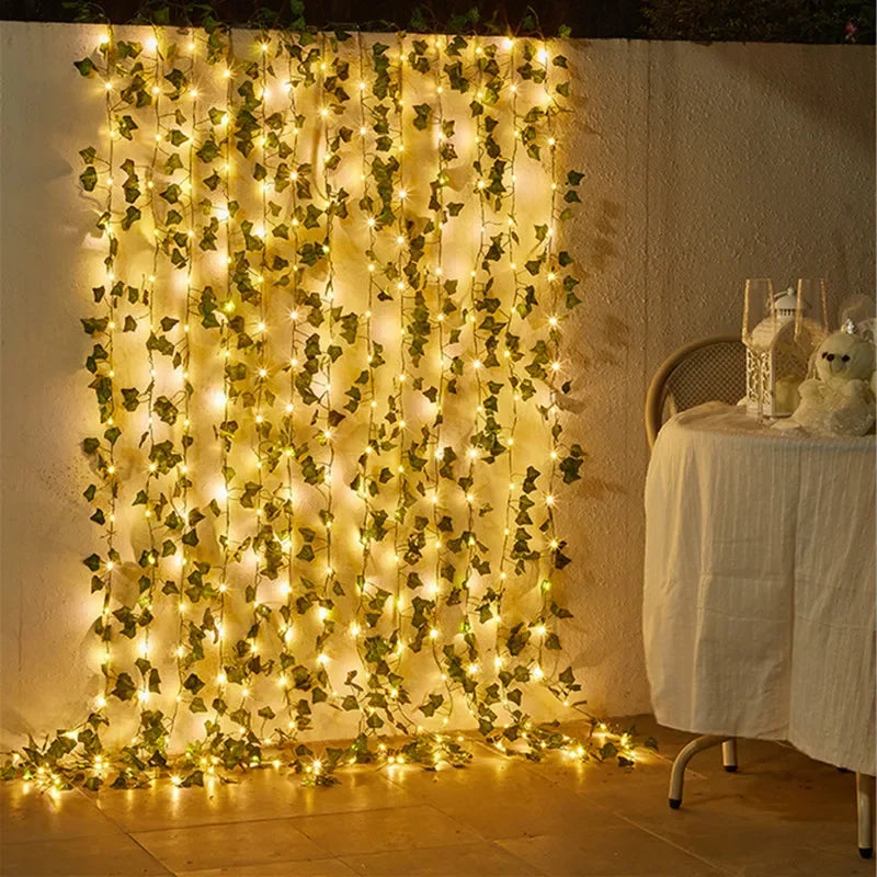 A vertical display of warm yellow string lights shaped like leaves decorating a white wall.
