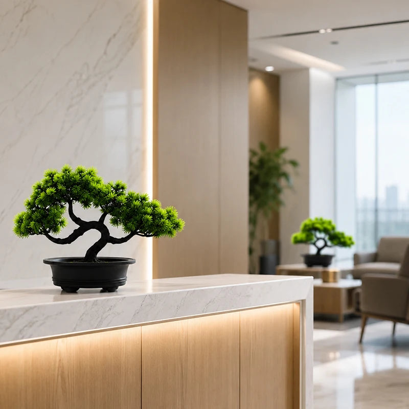An artificial bonsai pine tree in a black pot displayed on a modern marble countertop.