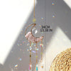 A handcrafted moon crystal suncatcher with a gold prism pendant hanging from a wooden branch.
