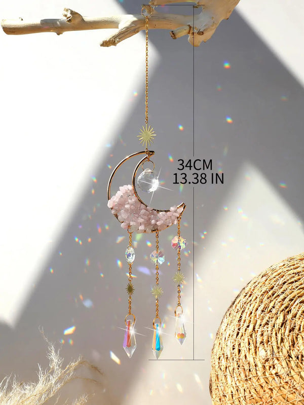 A handcrafted moon crystal suncatcher with a gold prism pendant hanging from a wooden branch.