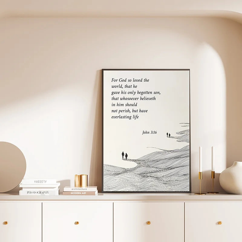 Black and white canvas art featuring John 3:16 scripture text on a light background displayed in a modern home setting.