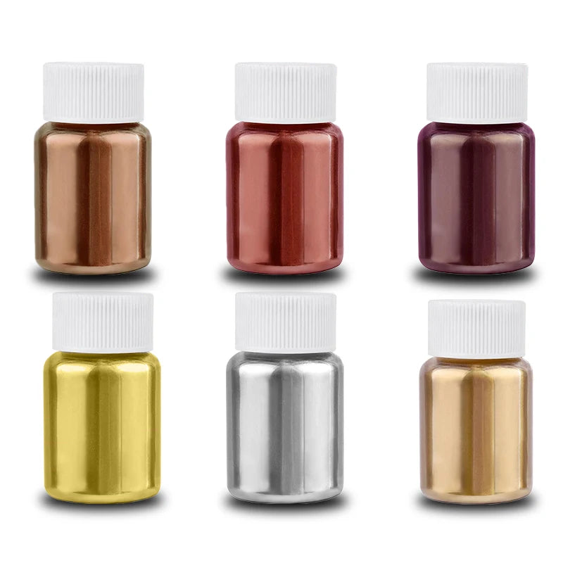 A collection of six glass bottles containing various shades of gold, silver, and purple glitter dust.