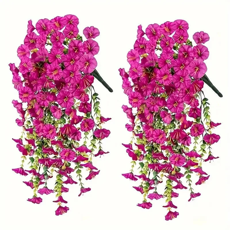 A bunch of artificial hanging morning glory flowers in vibrant pink and magenta with green eucalyptus leaves.