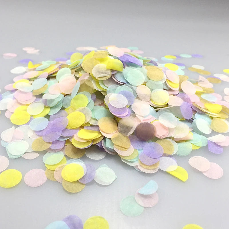 A pile of multicolor paper confetti in shades of yellow, pink, purple, and green scattered on a light surface.