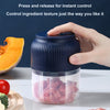 A hand is pressing a dark blue electric mini food chopper with a clear container filled with chopped ingredients.