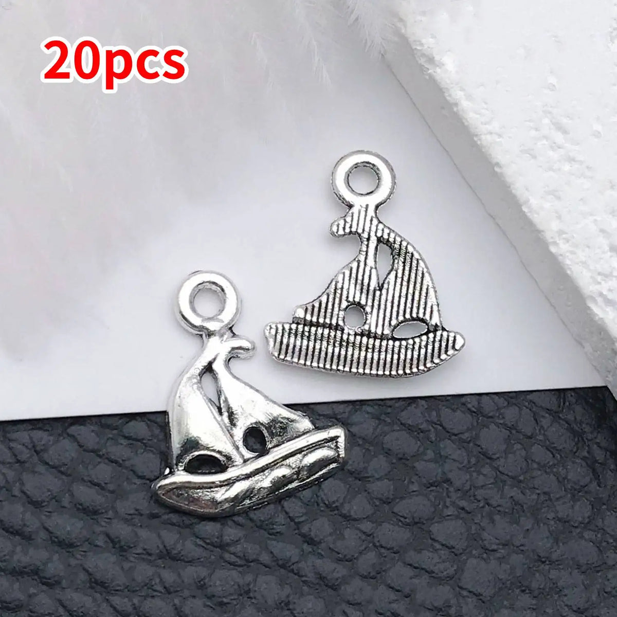 20 pieces of vintage ship anchor charms for jewelry making displayed on a dark surface.