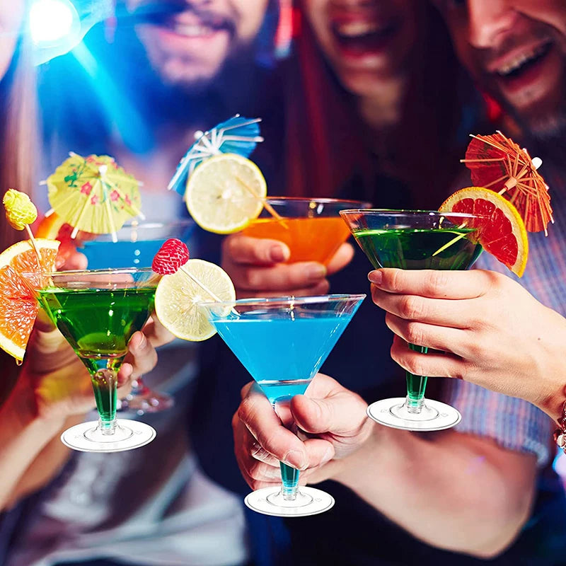 Hands hold colorful cocktails in martini glasses against a blurred background.