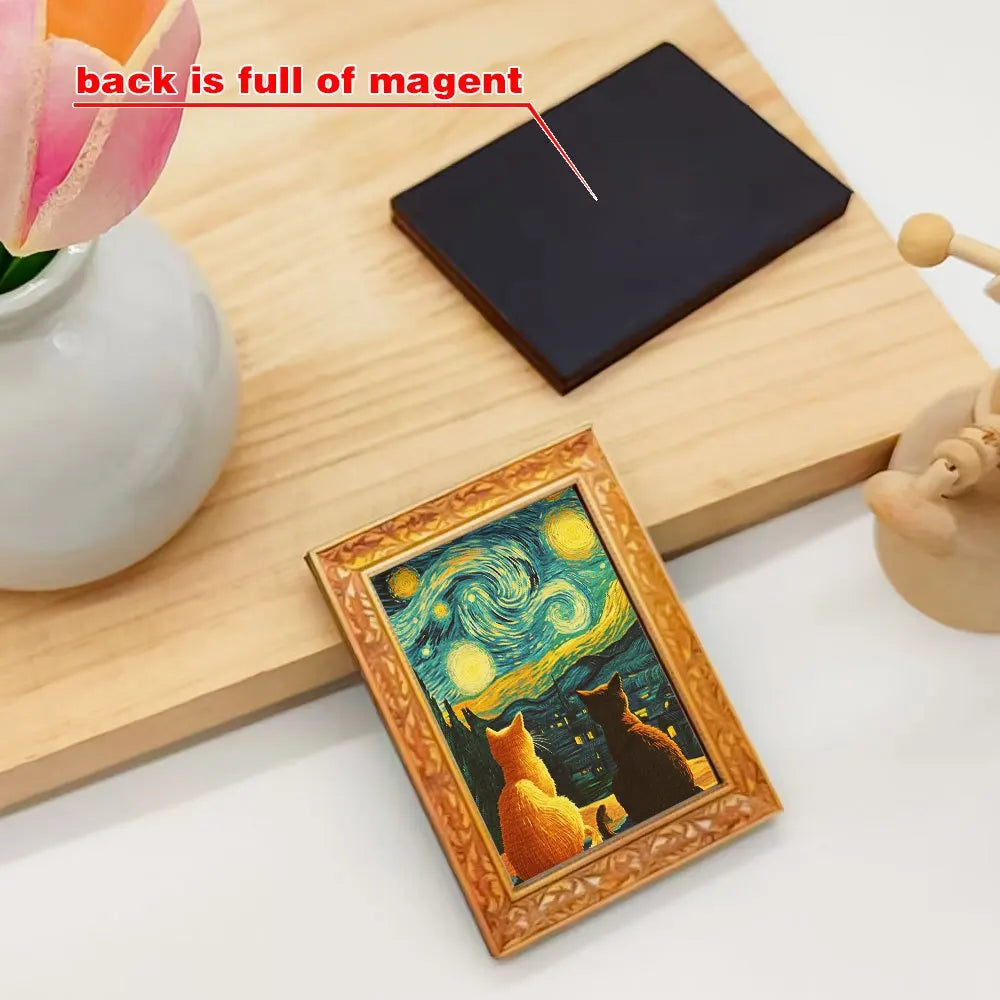 A wooden cutting board shows a dark magnet and a framed picture of cats under a starry sky.