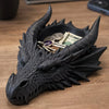 Sculpture de tête de dragon noir avec cornes et dents acérées, ornant des pièces et des clés.