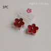 A single red soy wax flower tea light candle in clear packaging with a pink flower charm.