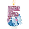 A large pink glitter number 5 candle with a blue bow decoration and a lit flame.