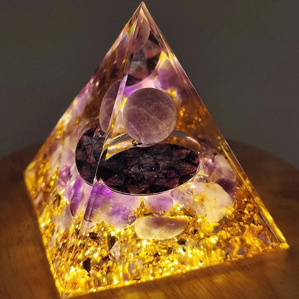 Handmade resin orgonite pyramid with natural obsidian and copper coil glowing yellow