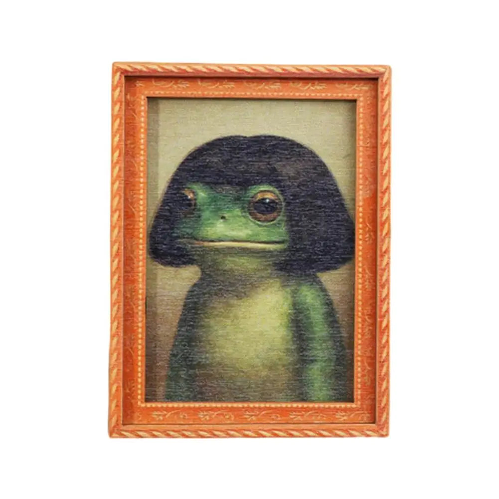 A framed painting of a green frog with dark hair, set in an orange wooden frame.