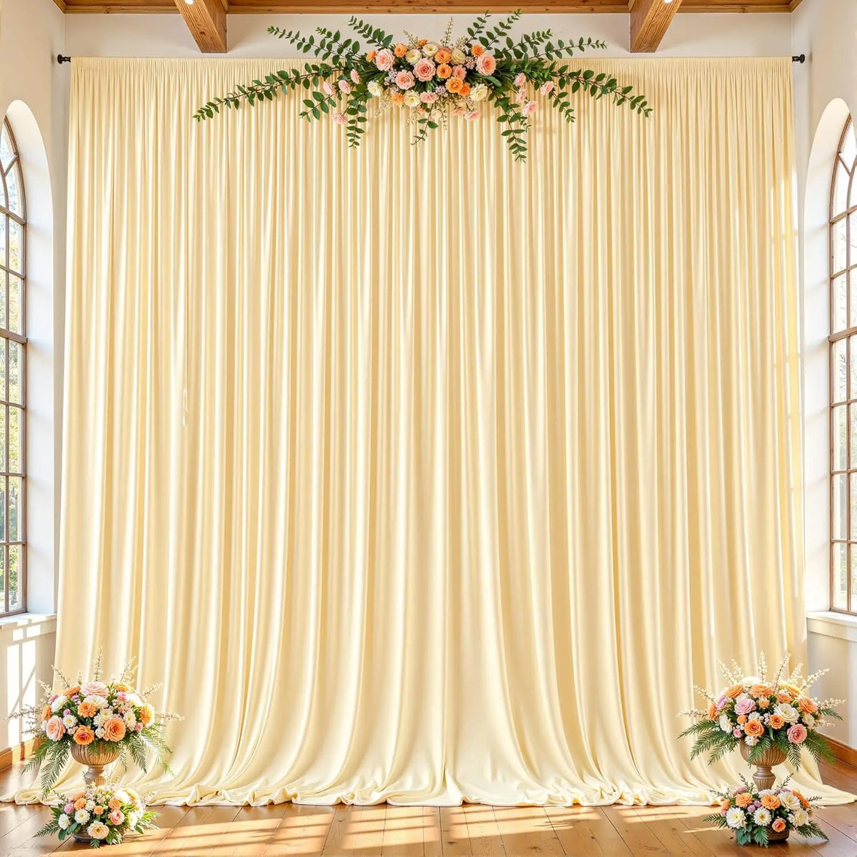A floor-to-ceiling cream fabric backdrop with vertical pleats and floral greenery for an event setting.