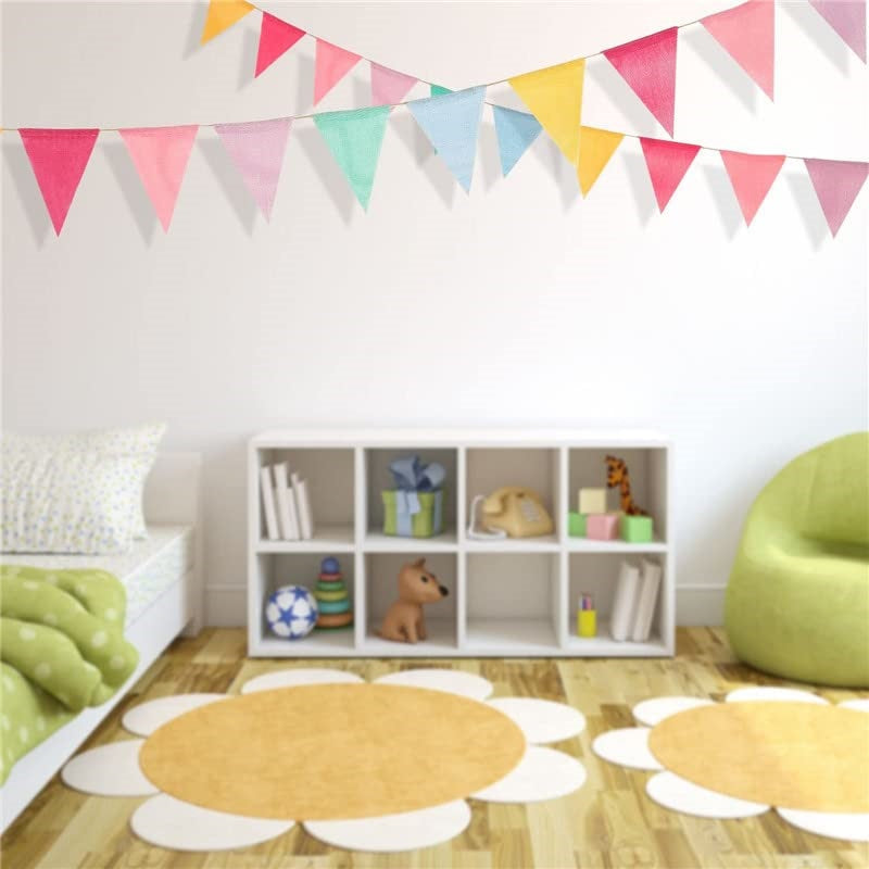 A display of a colorful jute linen pennant banner set hanging on a white wall above a wooden shelf.