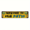 A wooden sign with palm leaves depicting the text Welcome to our patio in yellow and blue lettering.