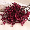 A branch of artificial deep pink or magenta baby's breath flowers used for fall decor