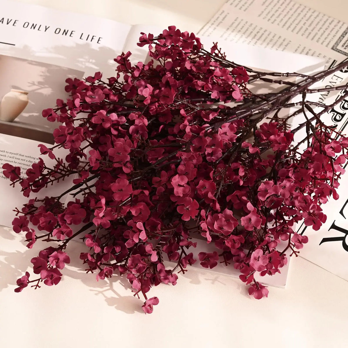 A branch of artificial deep pink or magenta baby's breath flowers used for fall decor