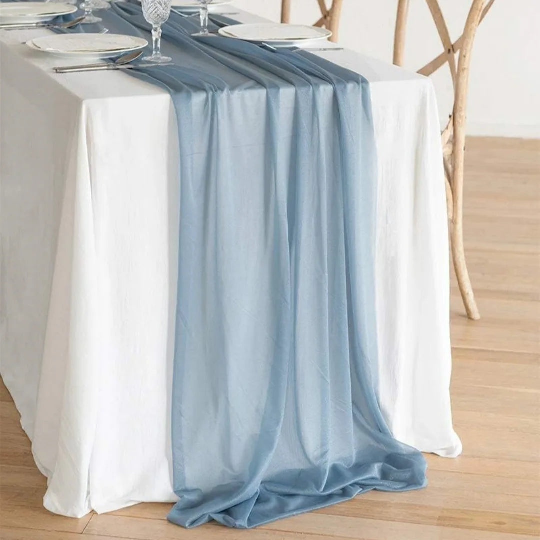 Light blue chiffon drape covering a white tablecloth at an event setting.