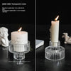 Porta velas de cristal transparente color verde azulado con una vela blanca sobre una superficie oscura.