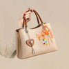 A light beige canvas tote bag with brown leather handles and colorful nylon rope charms is being held by a person.