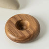 A round ceramic coffee mug with a wooden base resting on a white surface.