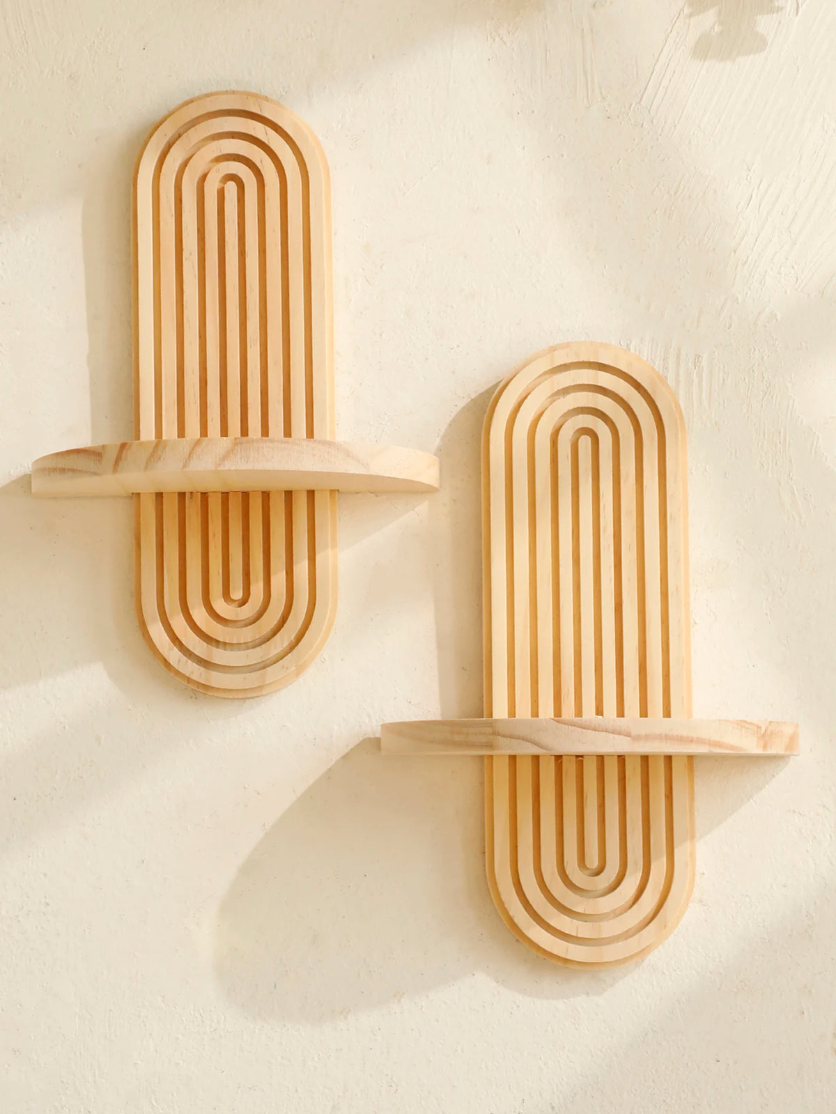 Two wooden wall shelves with concentric vertical grooves mounted on a light-colored wall.