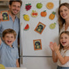 A refrigerator door decorated with various fruit magnets and a frog photo frame, surrounded by three smiling children.