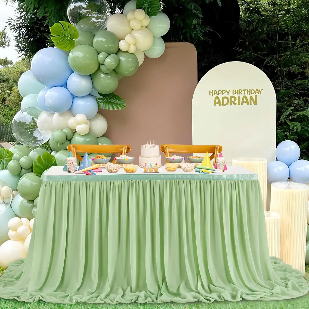 A green pleated polyester table skirt set up for a birthday celebration with balloons and decorations.