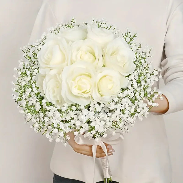 A bouquet of white roses and baby's breath flowers tied with a ribbon held by a person.
