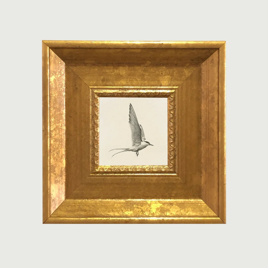 An elegant gold photo frame set with a framed bird silhouette inside.