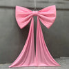 A pink satin bow with long tulle drapes hanging against a gray wall.