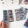 A hand holds a vertical photo card holder with transparent loose-leaf pages displaying various photos.