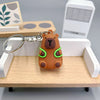Un pendentif de clé USB en forme de capybara orange est exposé sur un plateau en bois à côté d'un appareil électronique blanc