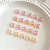 Una colección de 50 llamativos adornos de uñas de tortugas mini, dispuestos en círculo sobre una superficie blanca.