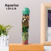 A tall glass bottle filled with green crystal and natural healing stones, topped with a jade-colored stopper.