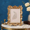 A golden 3D daisy resin photo frame with a delicate fern design displayed on a marble surface.