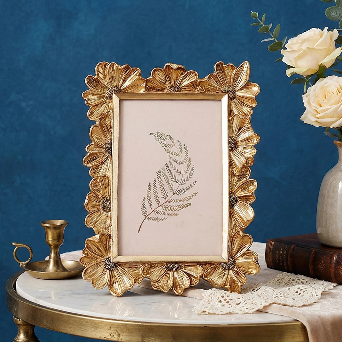A golden 3D daisy resin photo frame with a delicate fern design displayed on a marble surface.