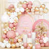 A large arrangement of pink, gold, and white latex balloons with bows for a birthday celebration backdrop.