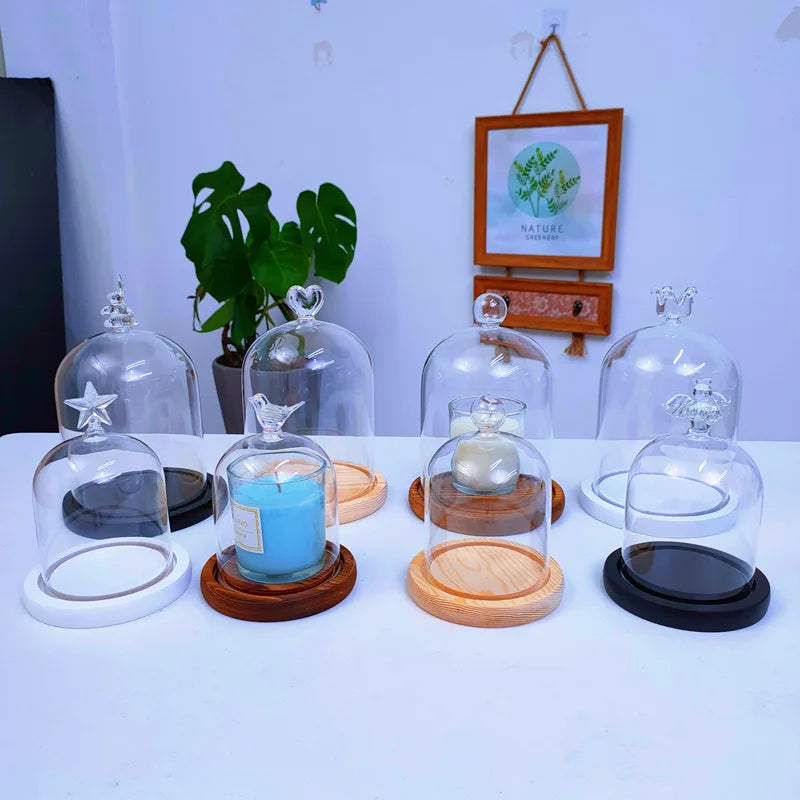 A collection of glass aromatherapy candle holders with wooden bases and dust-proof covers displayed on a white table.