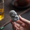 A hand holds a small, gray stone monk statue for meditation and Zen decor.