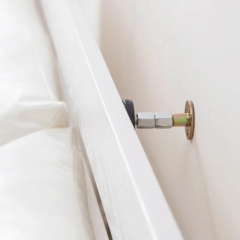 A close-up view of a silver adjustable bed stabilizer mechanism attached to a white wooden frame.