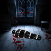 A realistic prop of a deceased victim wrapped in black plastic lies on a wooden floor stained with red blood.