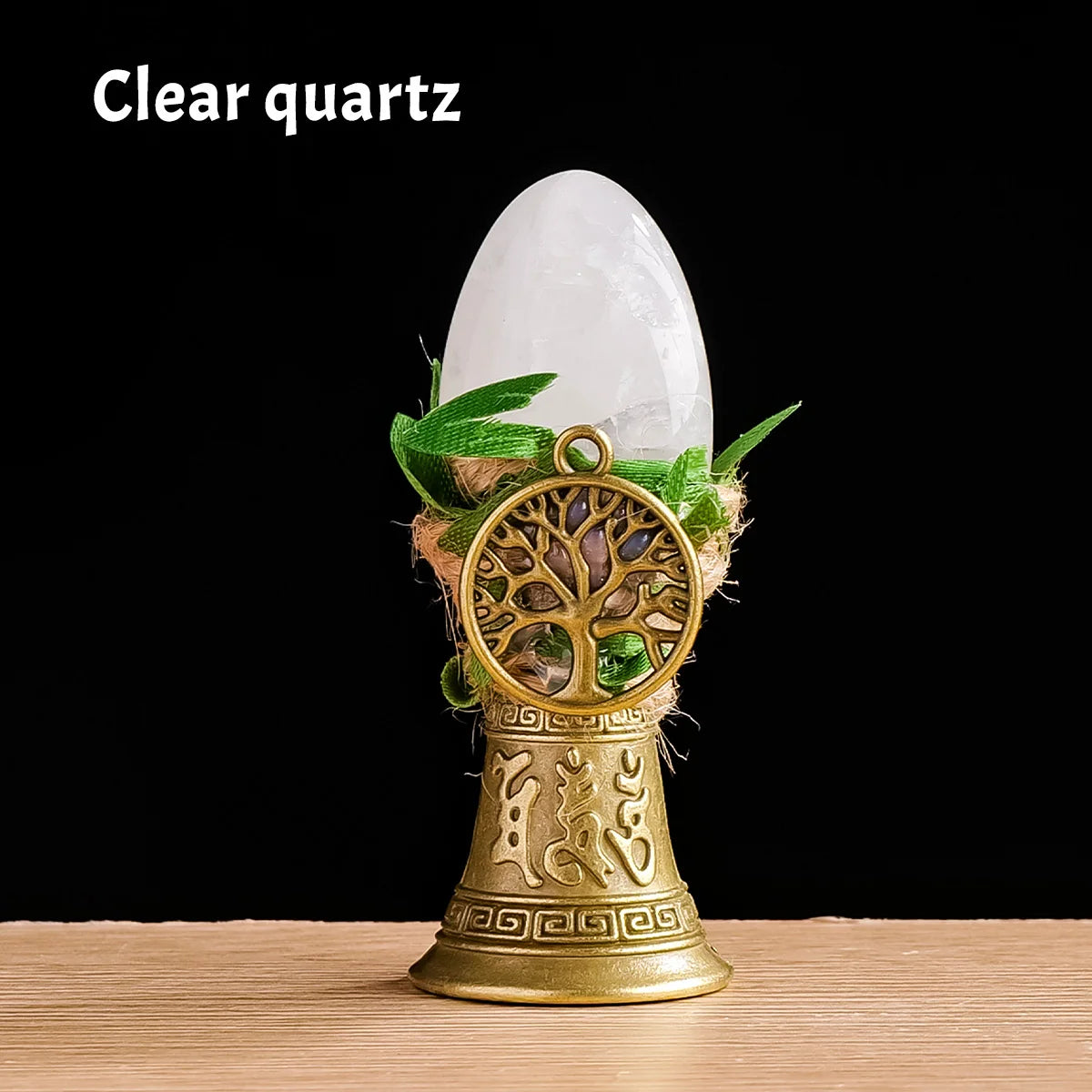 A clear quartz crystal is displayed atop a golden tree of life chime made of natural materials.