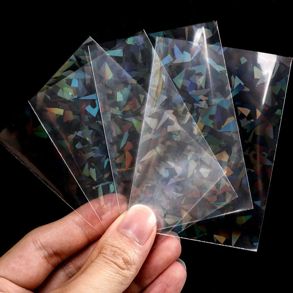 A hand holds several holographic card sleeves, clear plastic protectors for trading cards and photos.