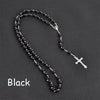 Black vintage cross and Virgin Mary pendant rosary necklace displayed on a dark background.