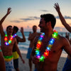 A man is smiling while wearing a colorful glow-in-the-dark LED Hawaiian lei necklace at a beach party.