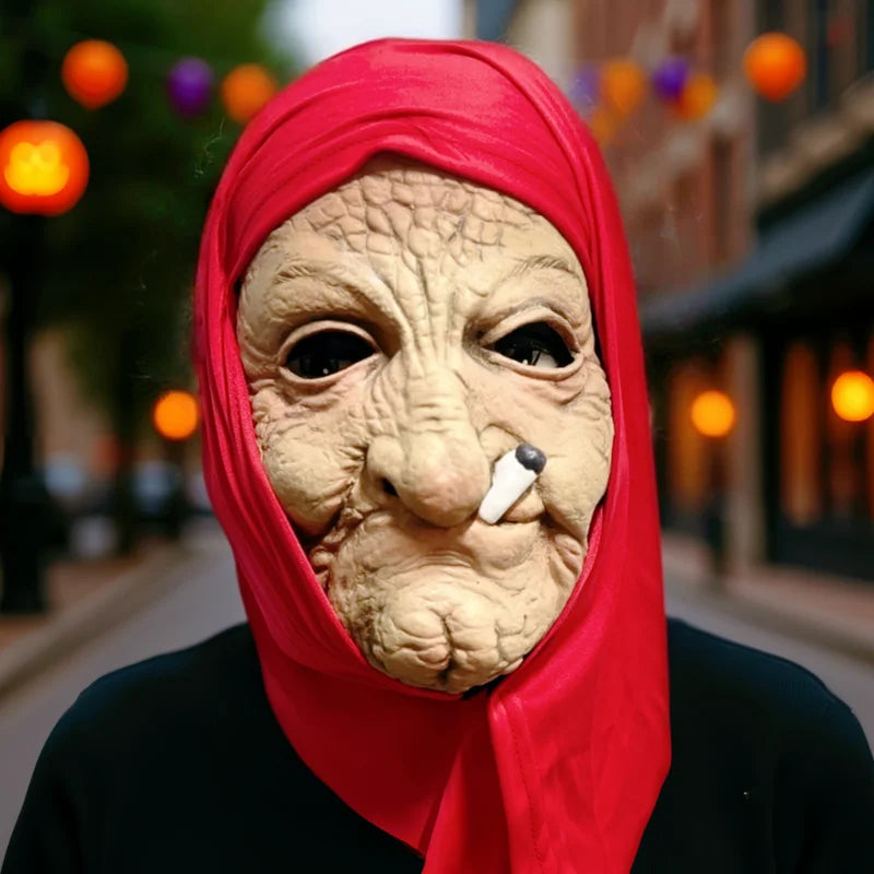 A woman wearing a red headscarf and a realistic full-face latex mask resembling an old, wrinkled face.
